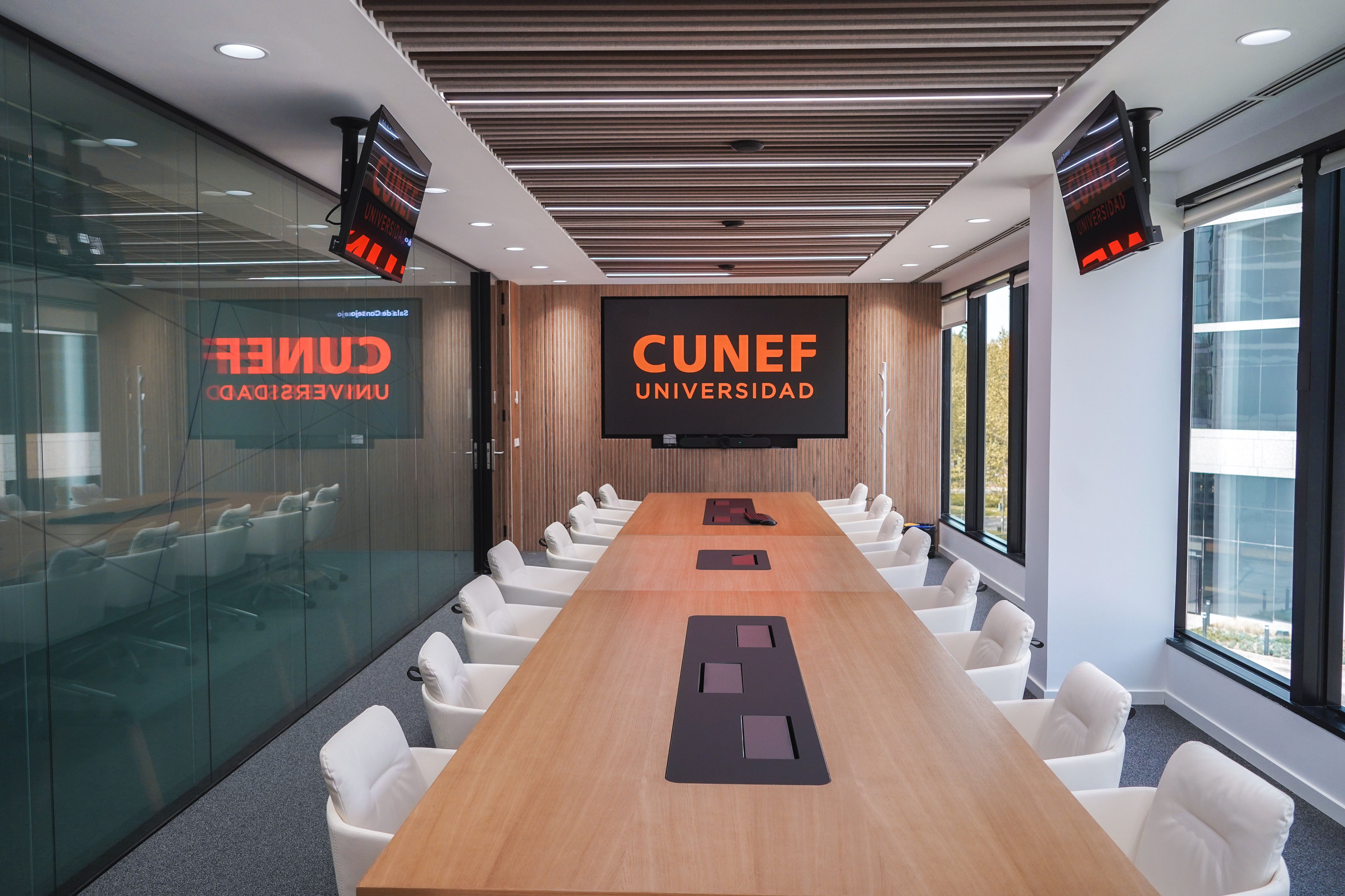 Sala de reuniones moderna en la universidad CUNEF con una larga mesa y tecnología audiovisual.