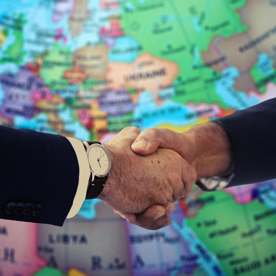 Dos personas se dan la mano frente a un mapa de Europa.