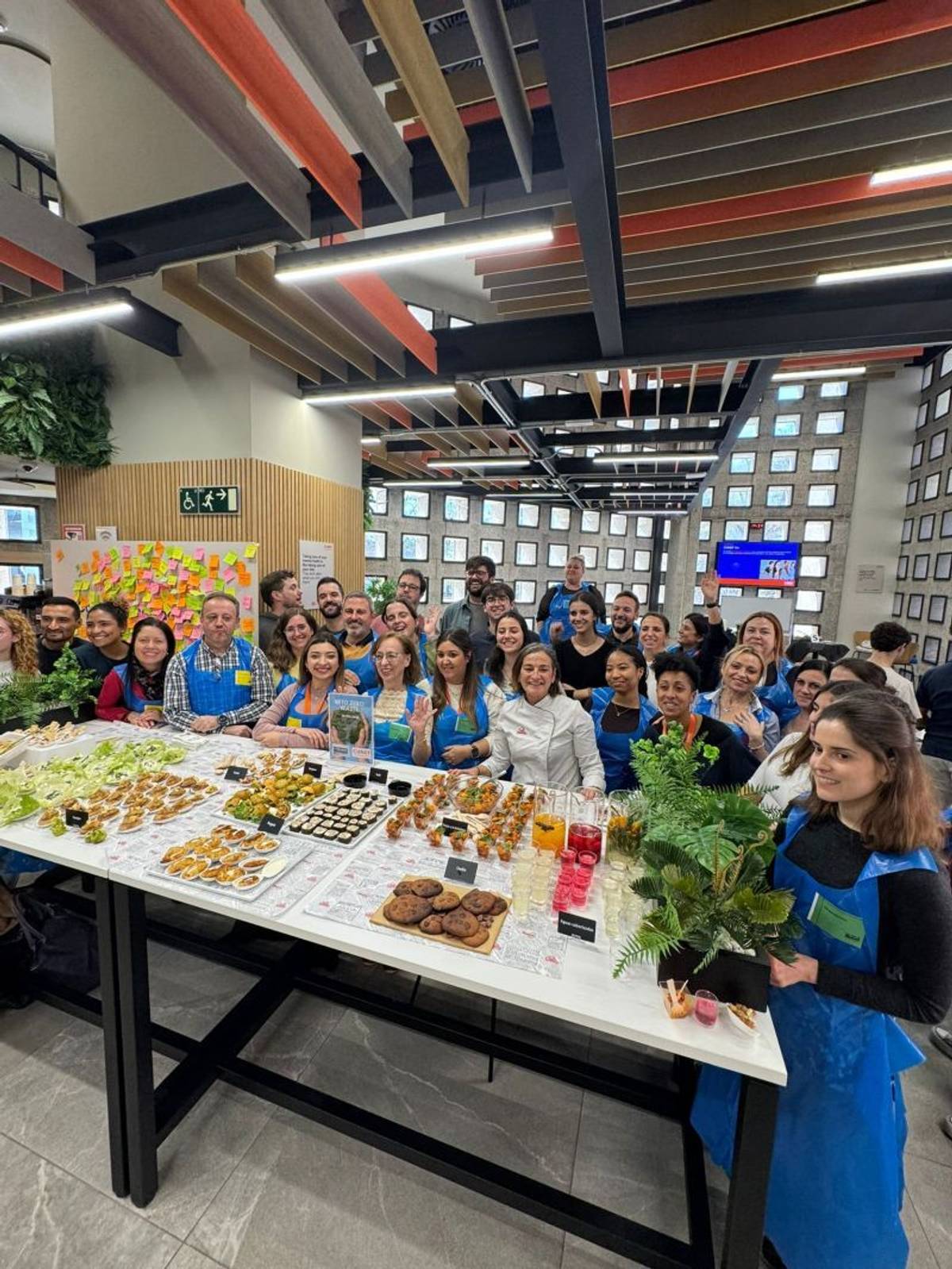 Un grupo de personas sonrientes se reúne en torno a una mesa llena de diferentes platillos y aperitivos.