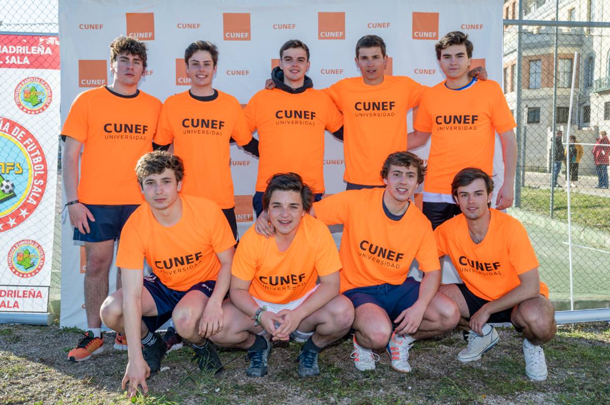 Un grupo de jóvenes sonrientes posando en un evento deportivo con camisetas naranjas.