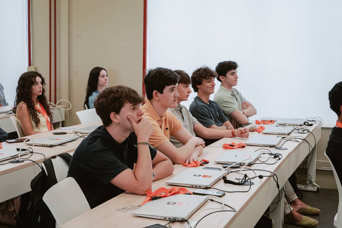 Un grupo de estudiantes escucha atentamente en un aula moderna.