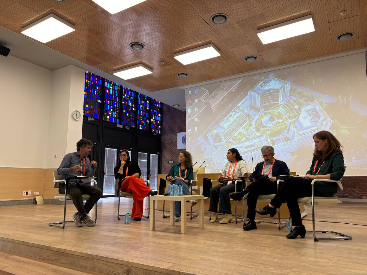 Una mesa redonda con varios panelistas discutiendo en un auditorio moderno.