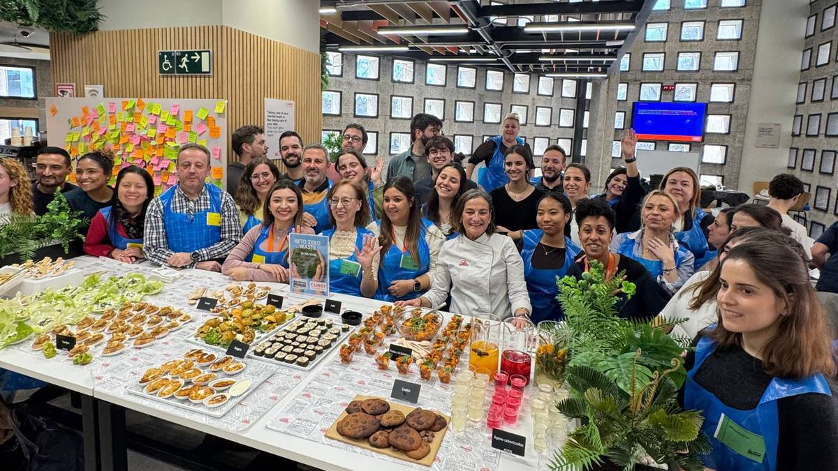 Un grupo de personas sonrientes se reúne en torno a una mesa llena de aperitivos en un ambiente festivo.