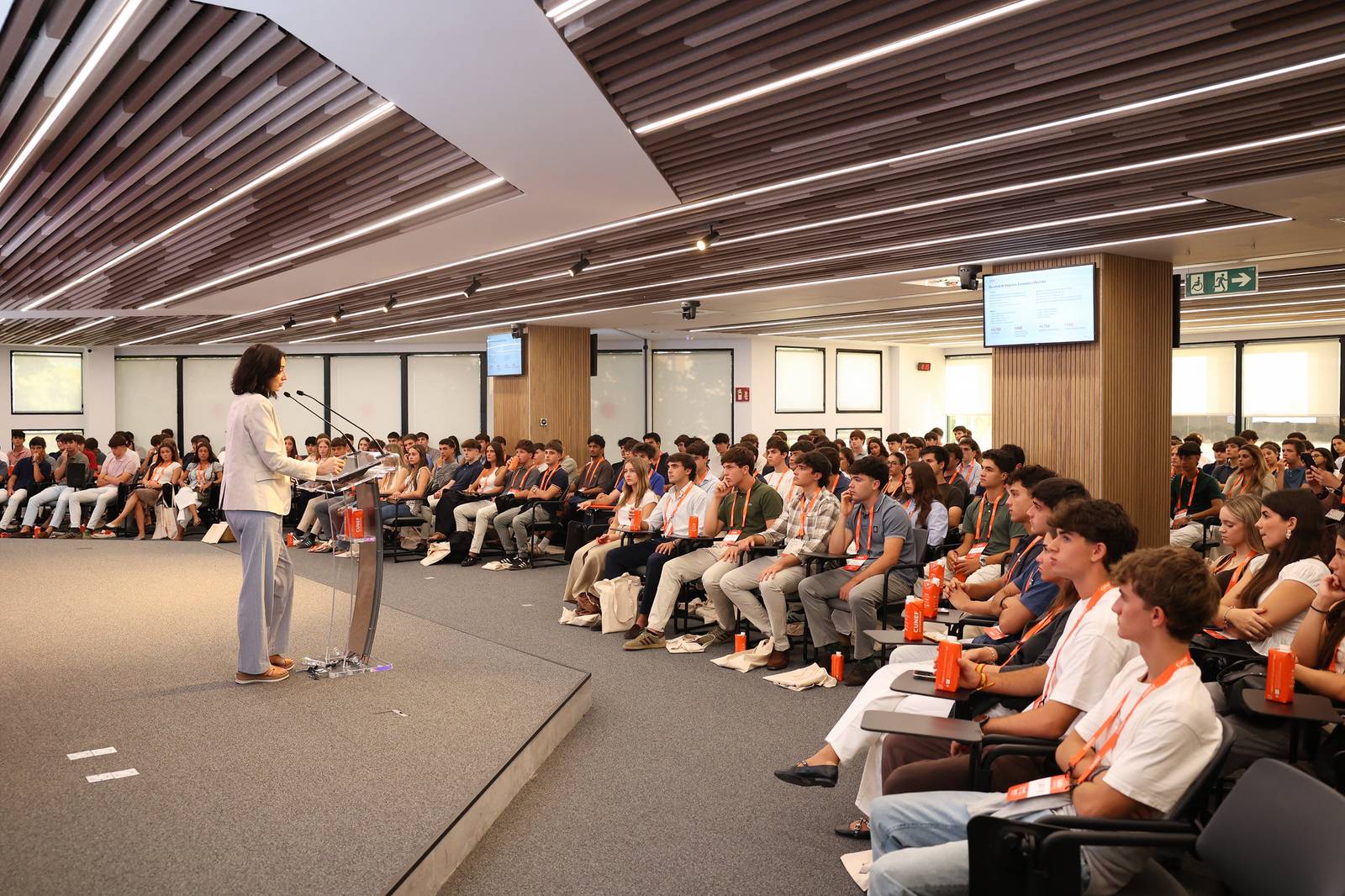 Una oradora se dirige a un numeroso público en un evento o conferencia.