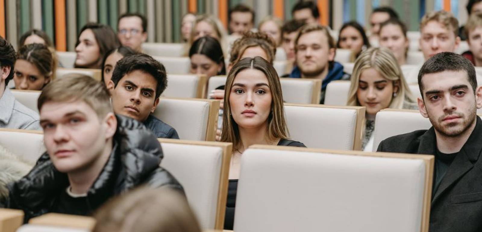 Un grupo de personas sentadas en un auditorio escuchando atentamente.