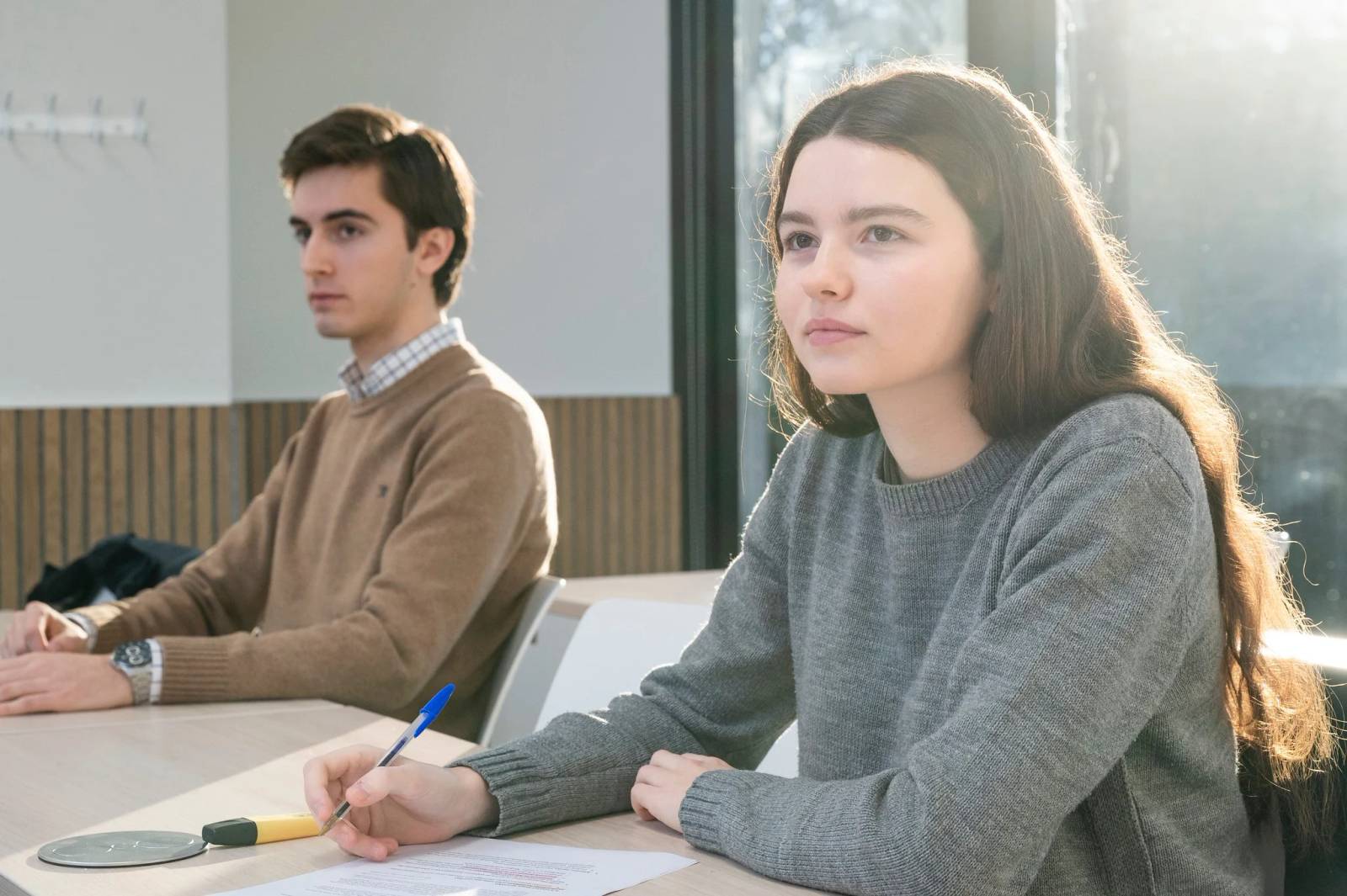Dos estudiantes sentados en un aula prestando atención durante una clase.