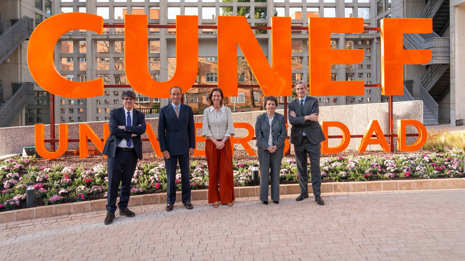 Un grupo de personas se encuentra frente a un gran cartel que dice 'CUNEF Universidad'.