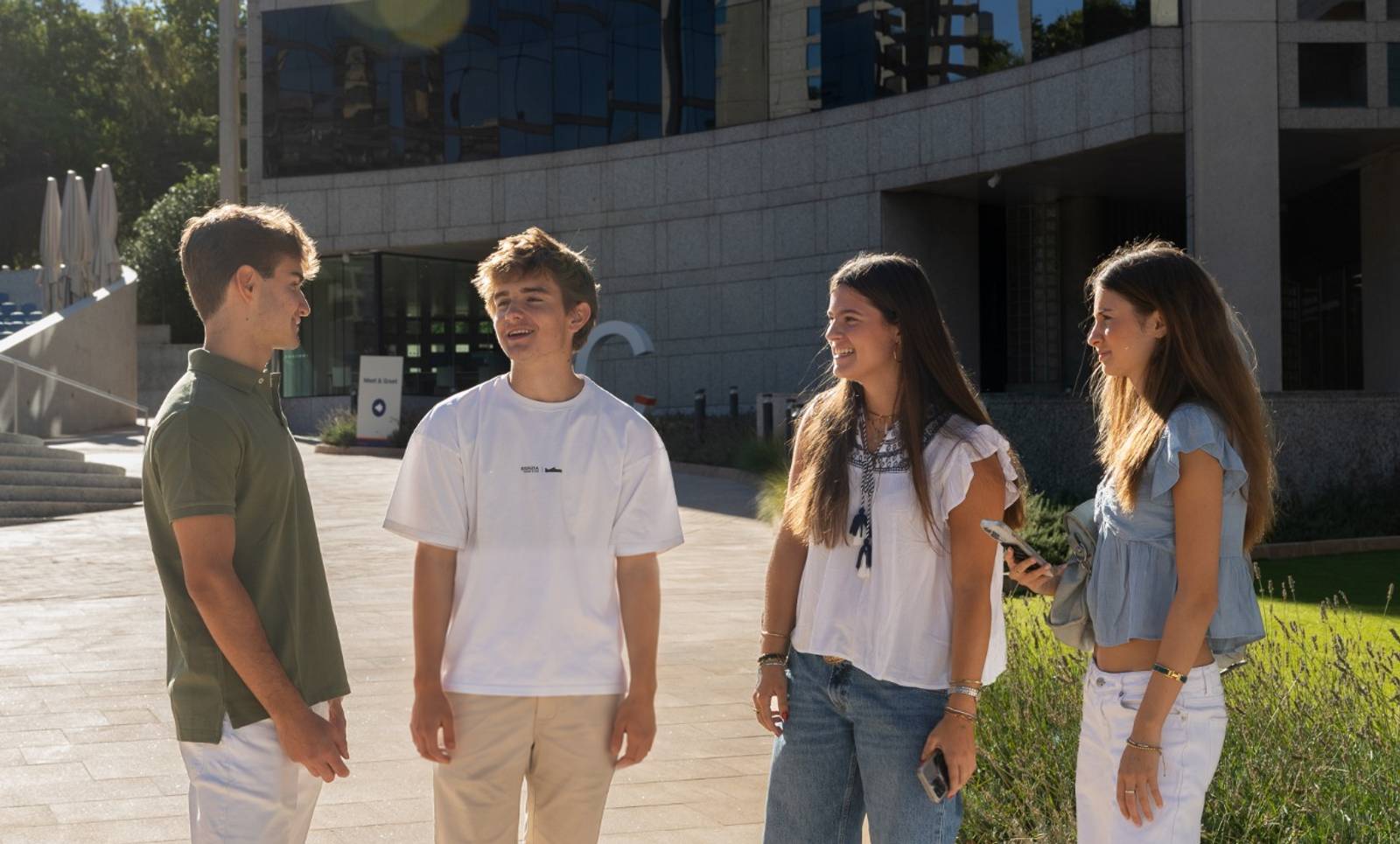 Grupo de cuatro jóvenes conversando al aire libre en un entorno urbano.