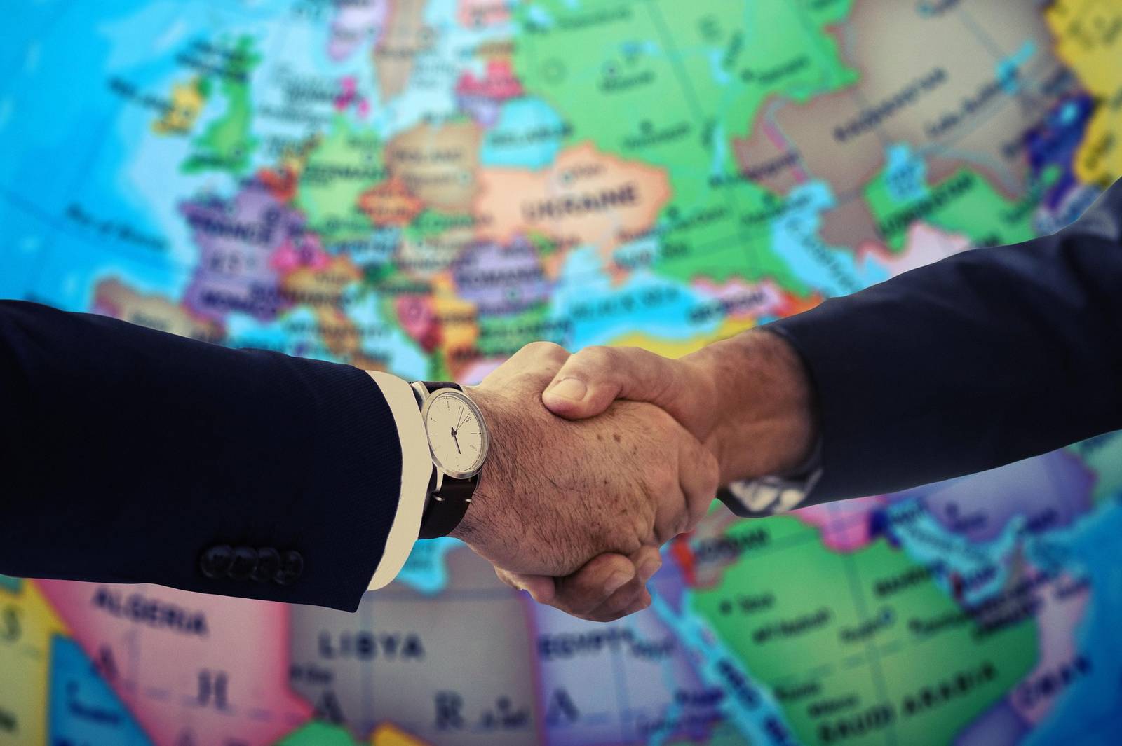 Dos personas se dan la mano frente a un mapa de Europa.
