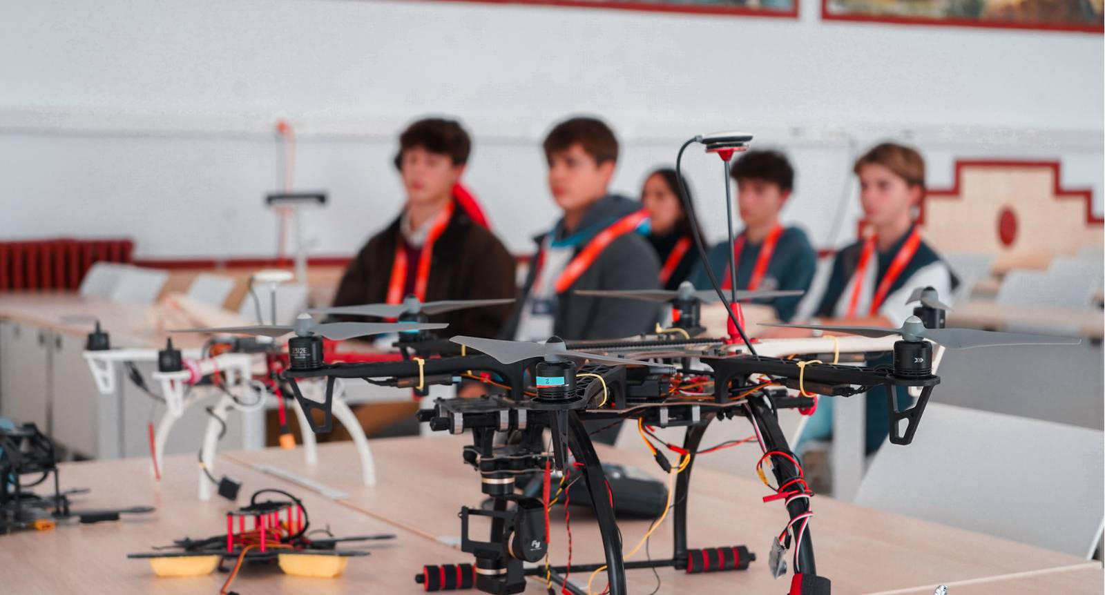 Un grupo de jóvenes observa un dron en un aula.