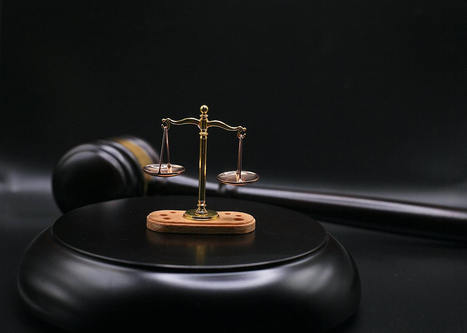 La imagen muestra una balanza de la justicia sobre una base, junto a un mazo de juez.