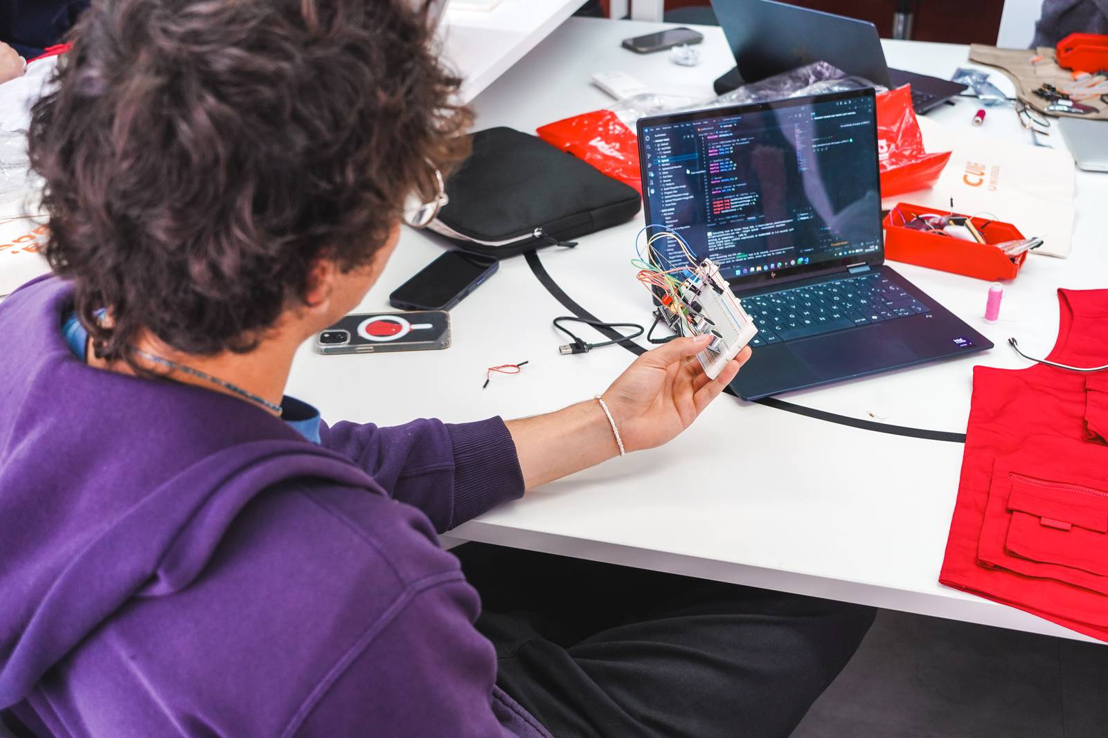 Una persona está trabajando en un proyecto de electrónica frente a una computadora portátil.