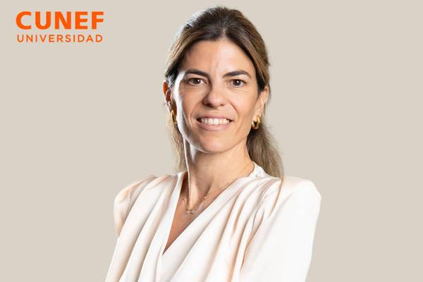 Retrato de una mujer sonriente con fondo claro, vestida con una blusa blanca.