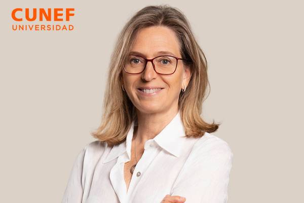 Mujer sonriendo con camisa blanca y gafas, en un fondo neutro.