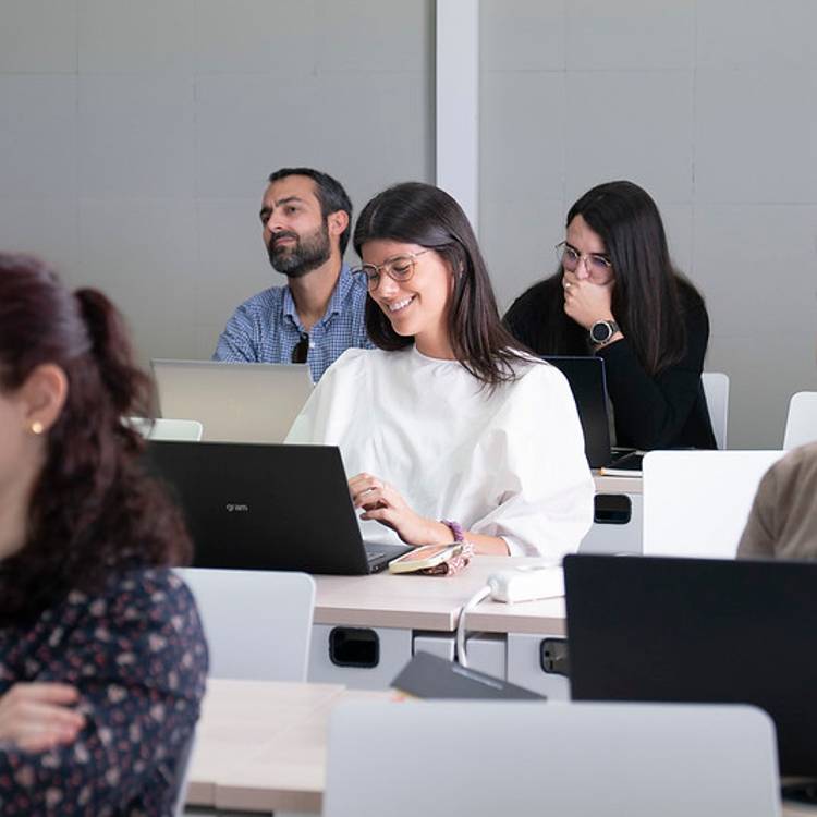 Un grupo de personas sentadas en un aula mientras asisten a una presentación.