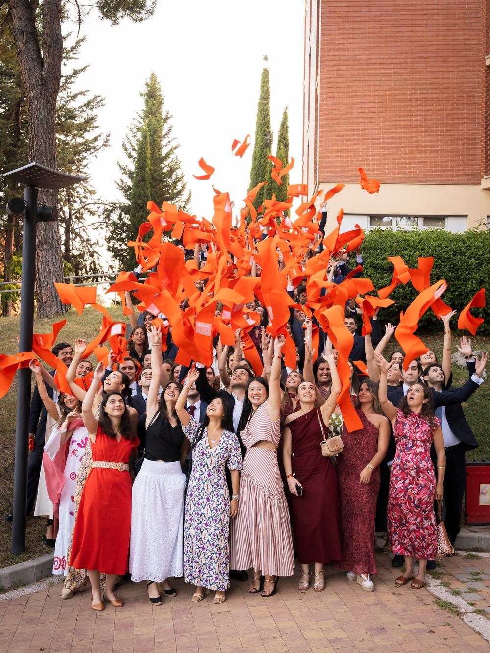 Un grupo de personas celebra lanzando cintas naranjas al aire en un evento festivo.