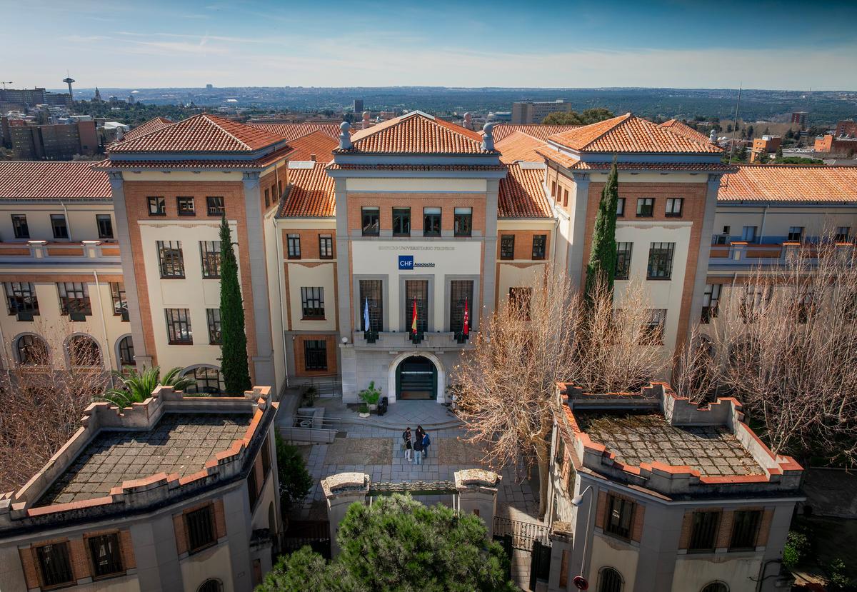 Una vista aérea del Campus Pirineos, rodeado de vegetación y un paisaje urbano al fondo.