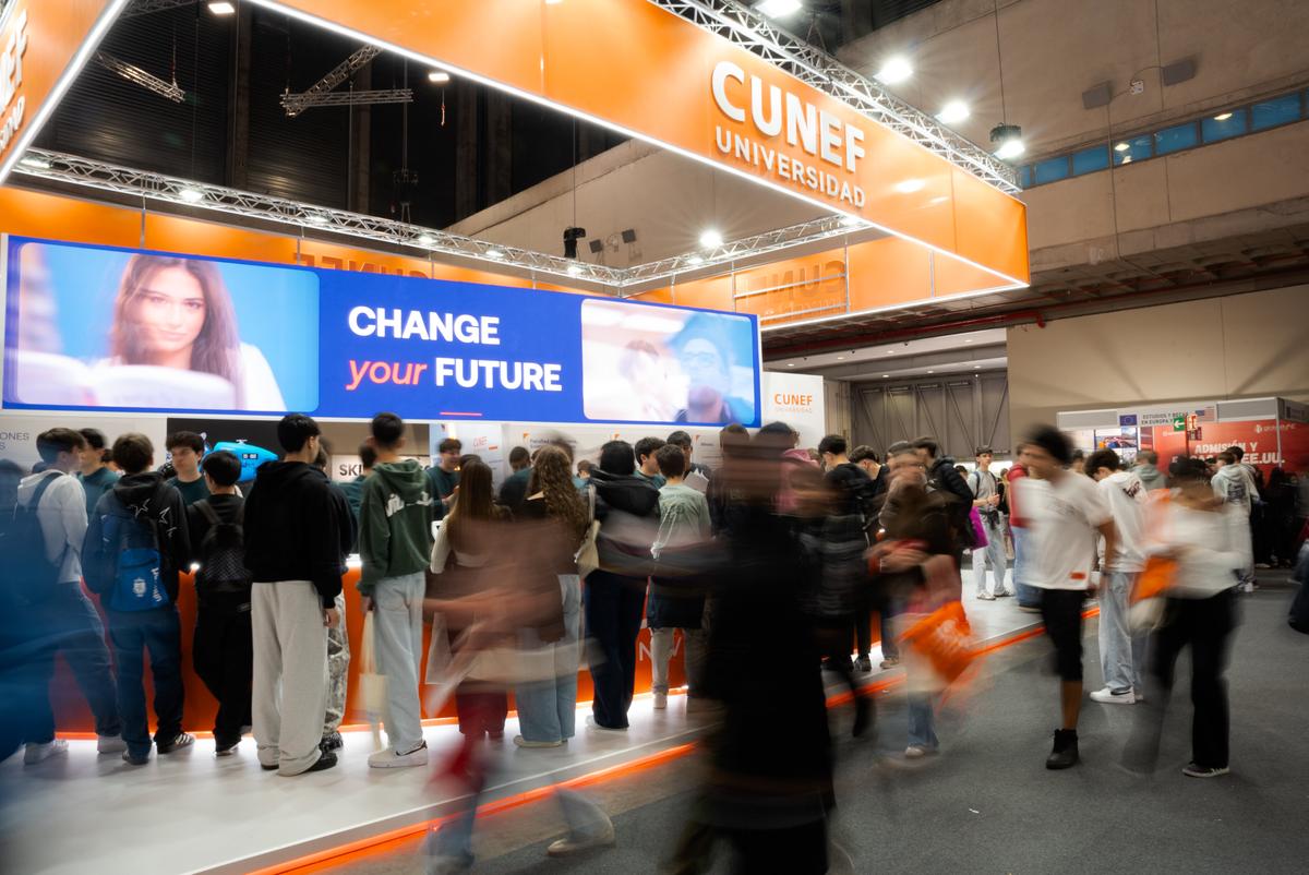 Un grupo de personas se concentra en un stand universitario durante una feria educativa.