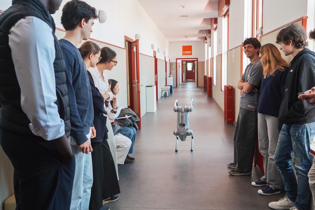 Un grupo de personas observa a un robot en un pasillo escolar.
