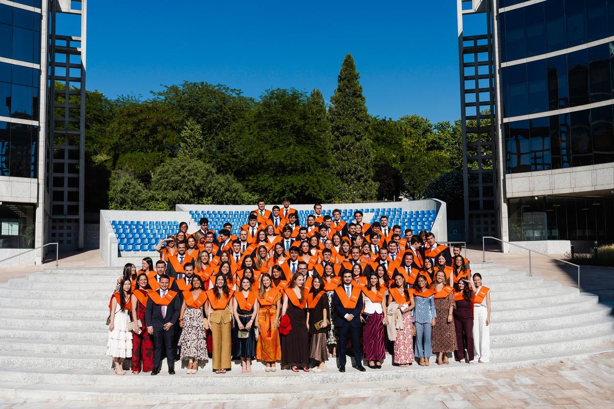 Un grupo de graduados posando en escaleras con togas y birretes.