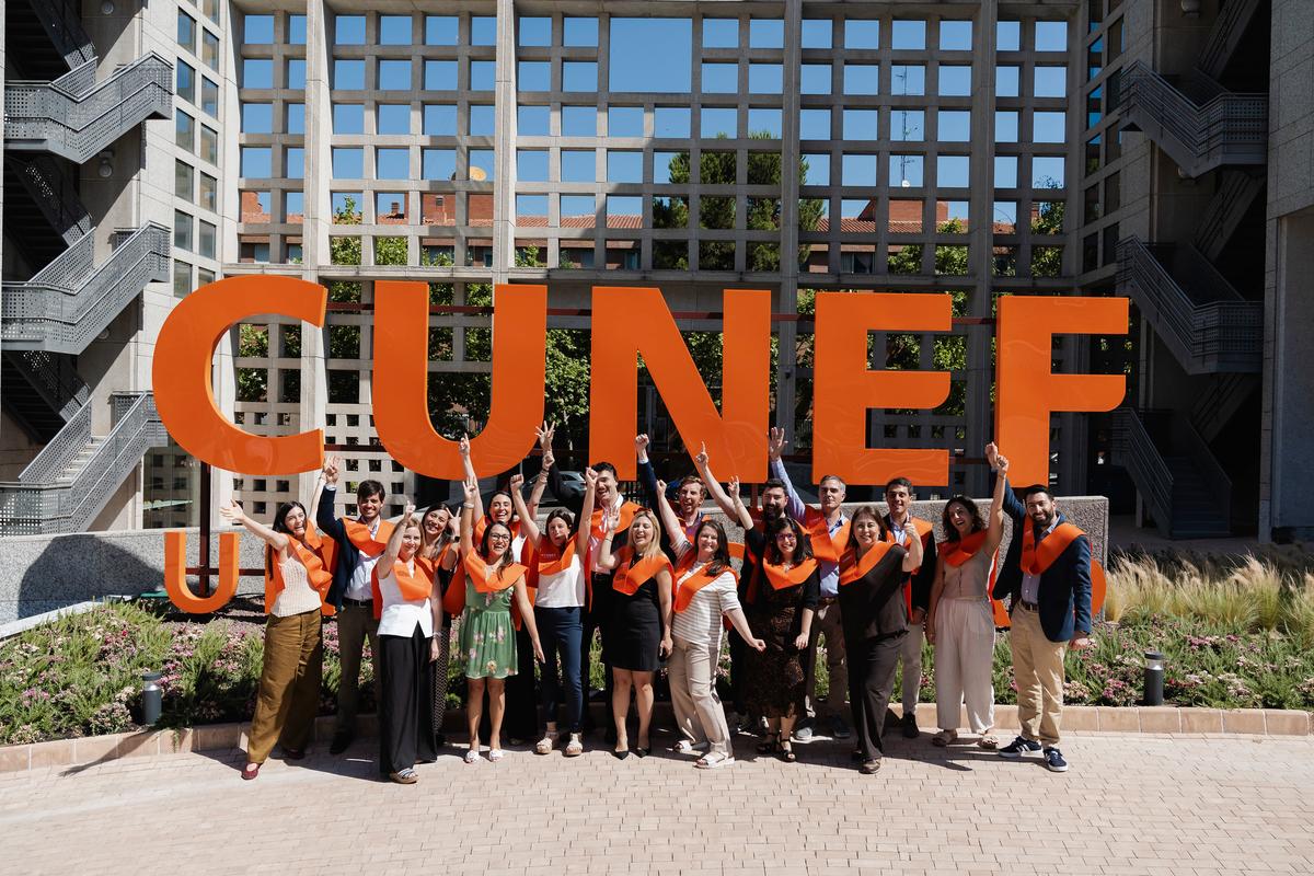 Un grupo de personas celebra frente a un gran letrero que dice 'CUNEF'.