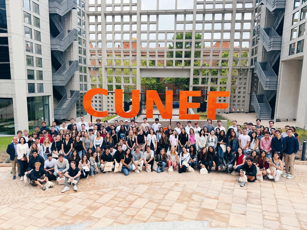 Un gran grupo de estudiantes poses ante un letrero naranja que dice CUNEF.