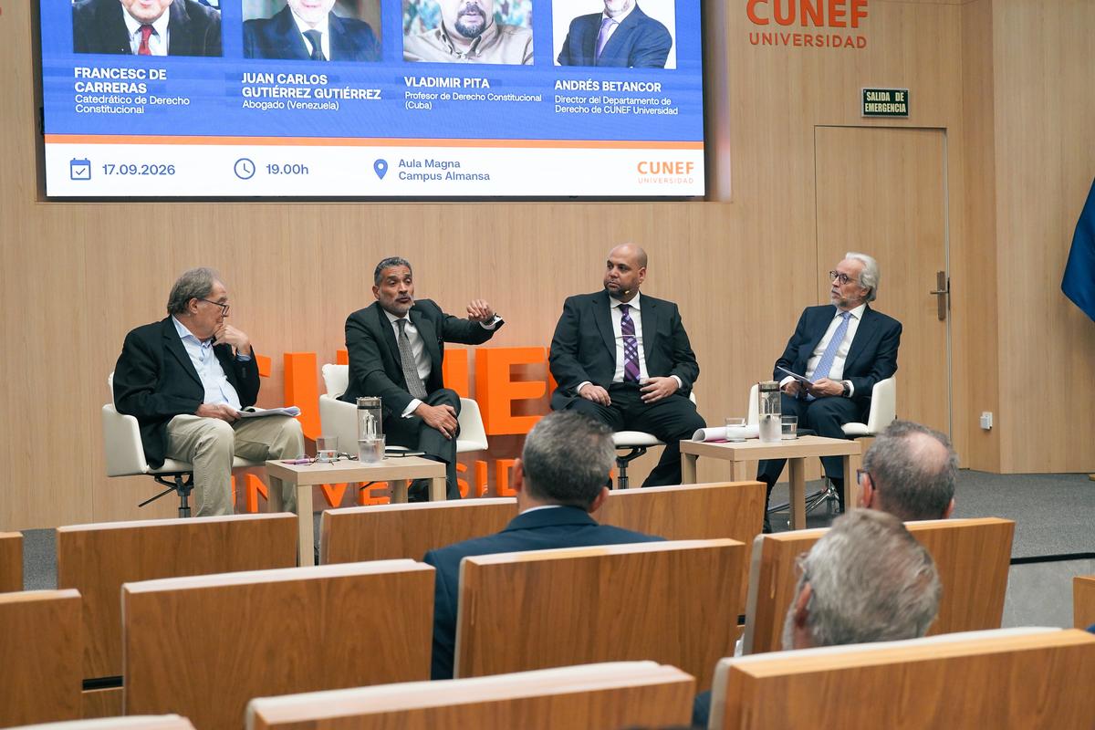 Un panel de discusión con cuatro ponentes sentados en una mesa en una universidad.