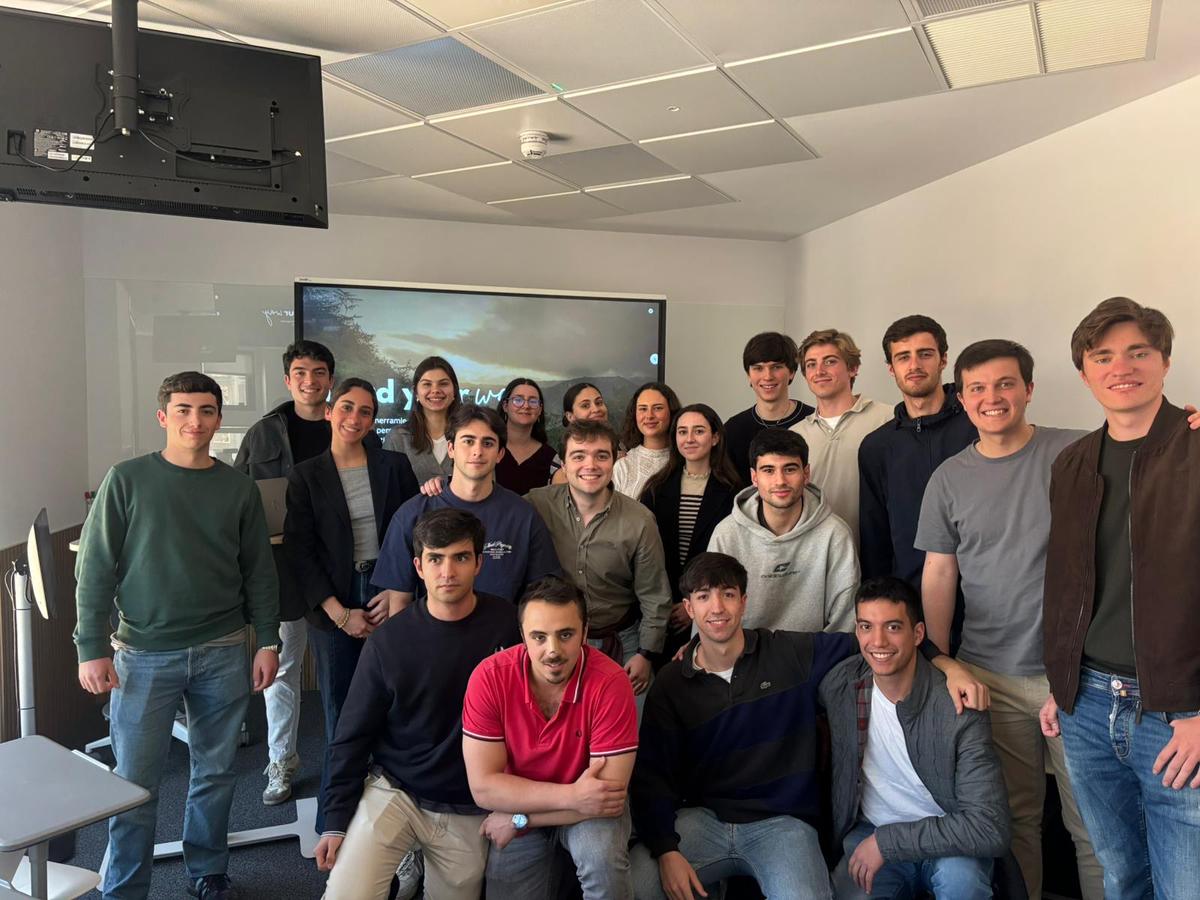Grupo de estudiantes posando juntos en un aula con una pantalla al fondo.