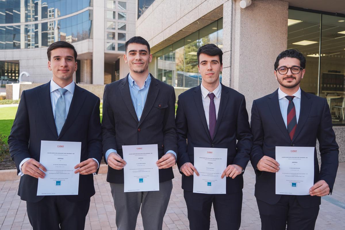Cuatro jóvenes en traje sosteniendo certificados en un entorno urbano.