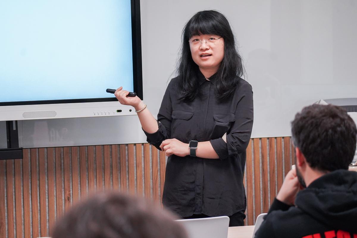 Una persona presenta información ante un grupo de escucha en un salón de clases.