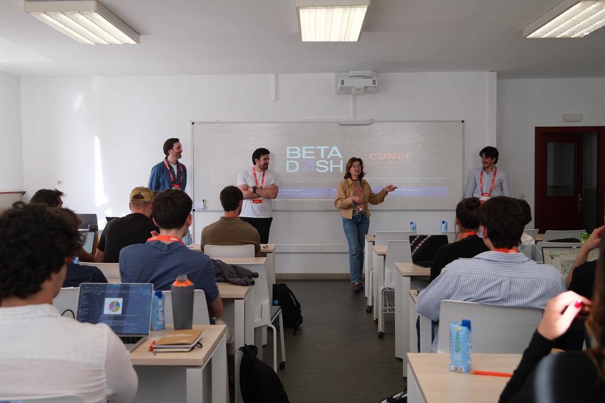 Un grupo de personas presenta un proyecto en un aula con estudiantes atentos.