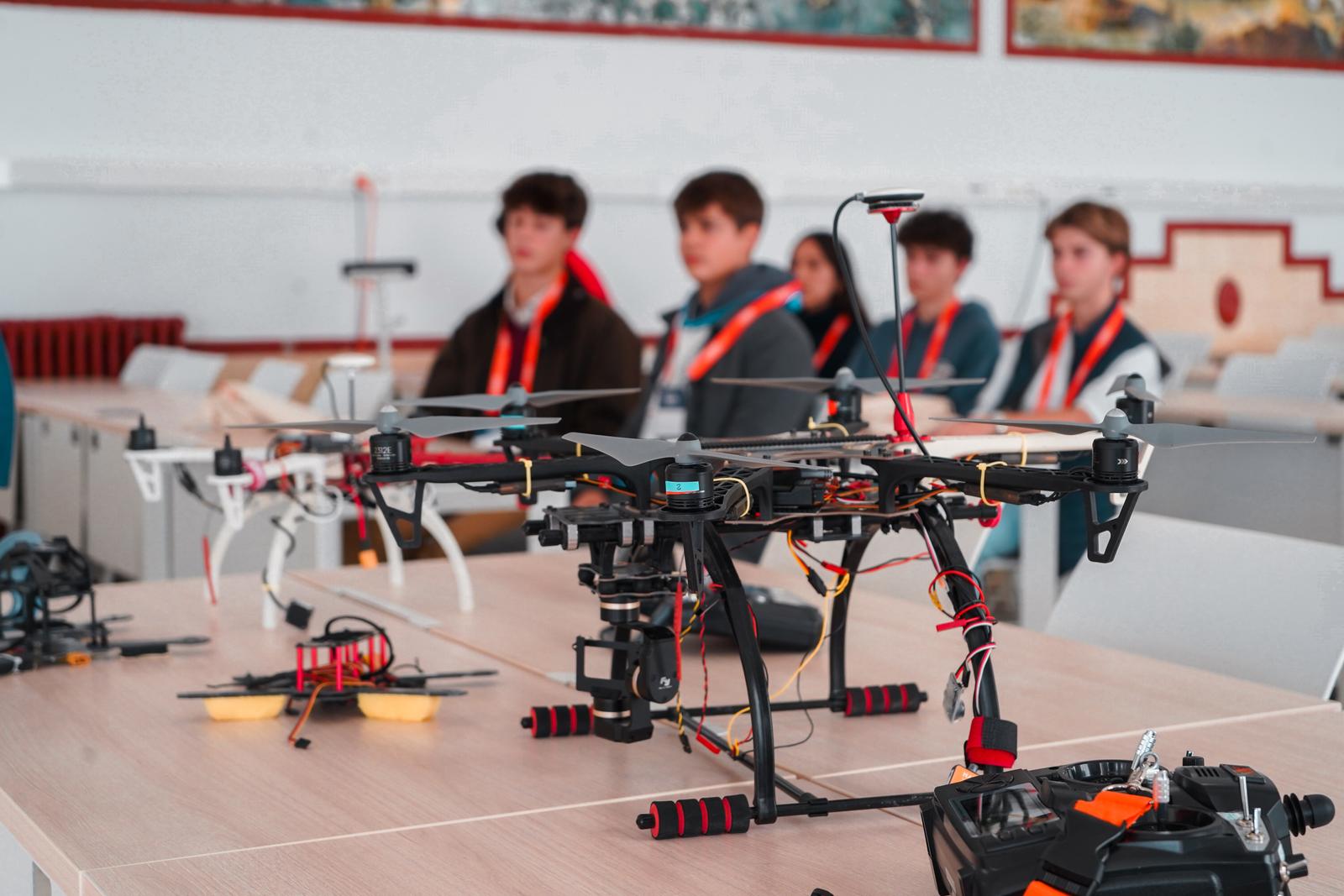 Un grupo de estudiantes observa un dron en una aula equipada con tecnología.