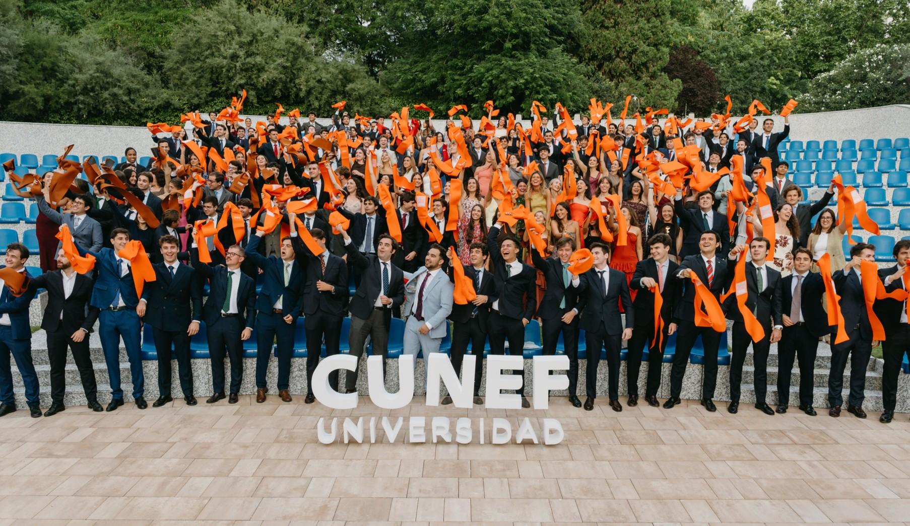Un grupo de graduados celebra con bufandas naranjas en la universidad CUNEF.
