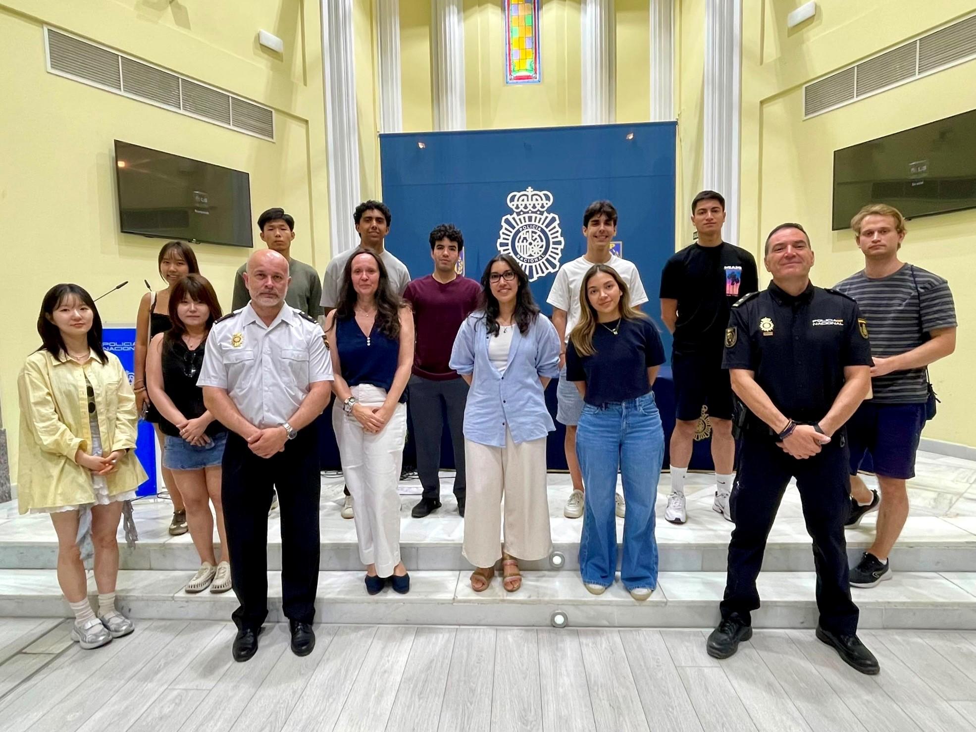 Un grupo de personas posando en un interior con decoraciones y una insignia en la pared.
