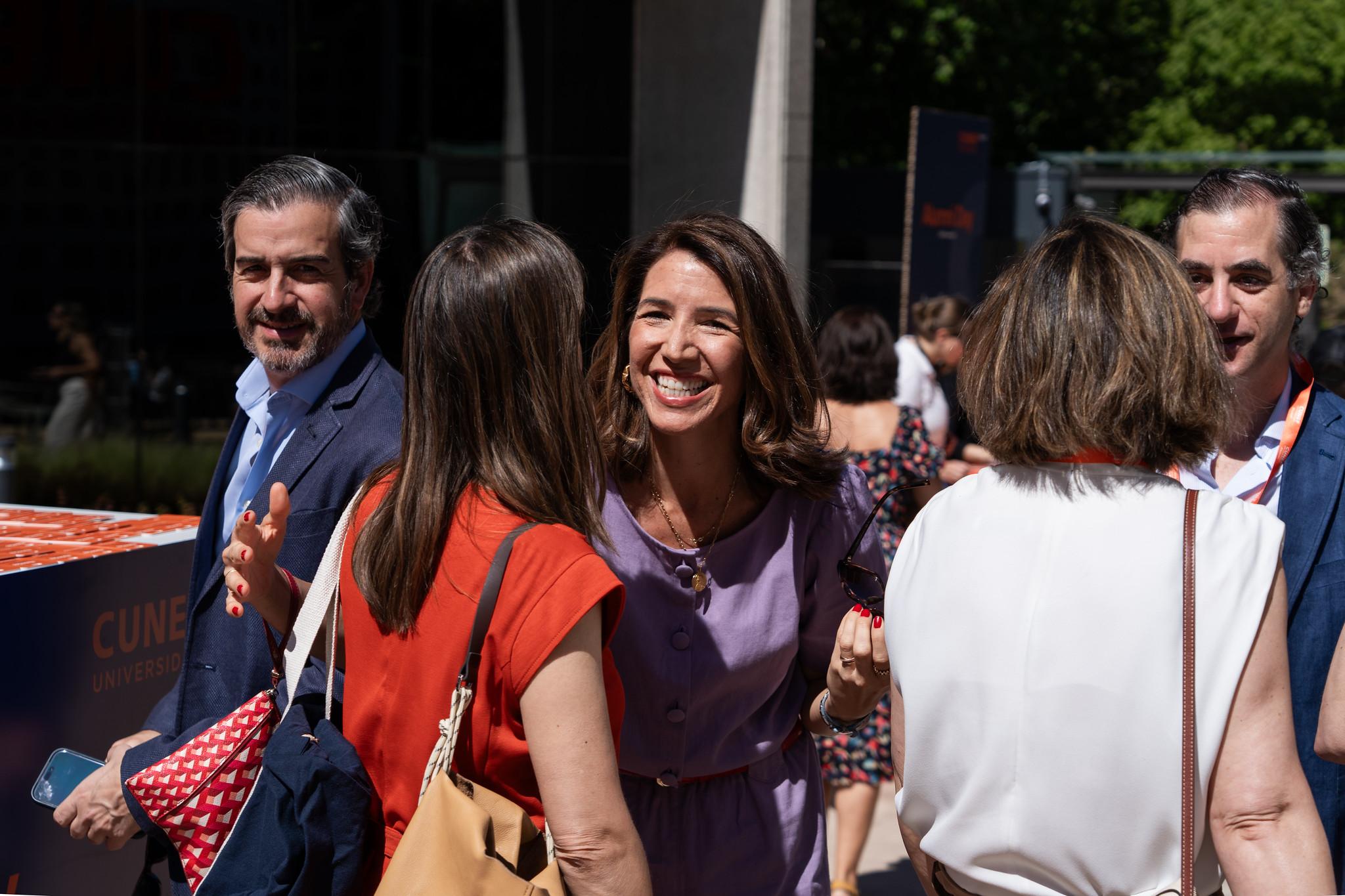 Un grupo de personas sonríe y se saluda en un evento al aire libre.