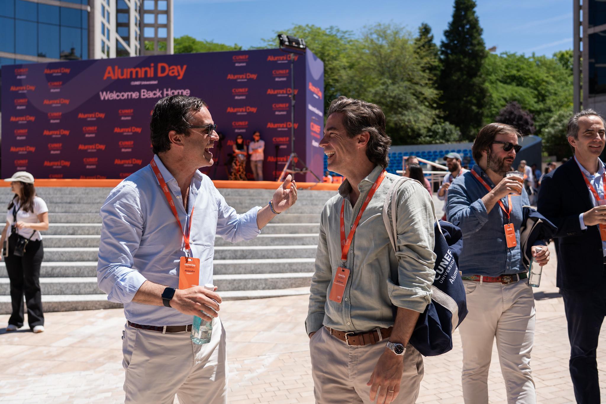 Un grupo de hombres conversando animadamente en un evento al aire libre.