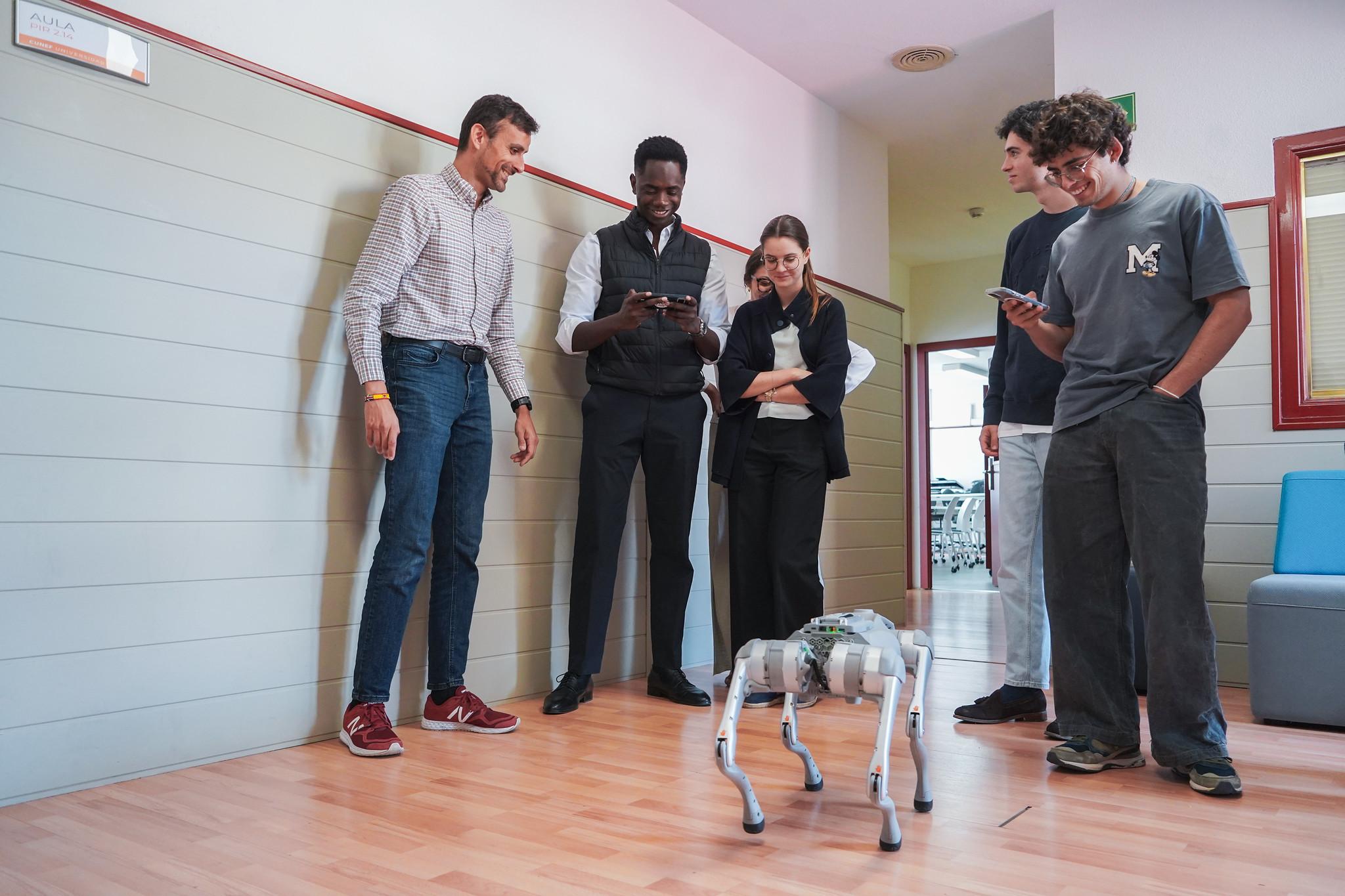 Un grupo de personas observa a un perro robot en un pasillo.