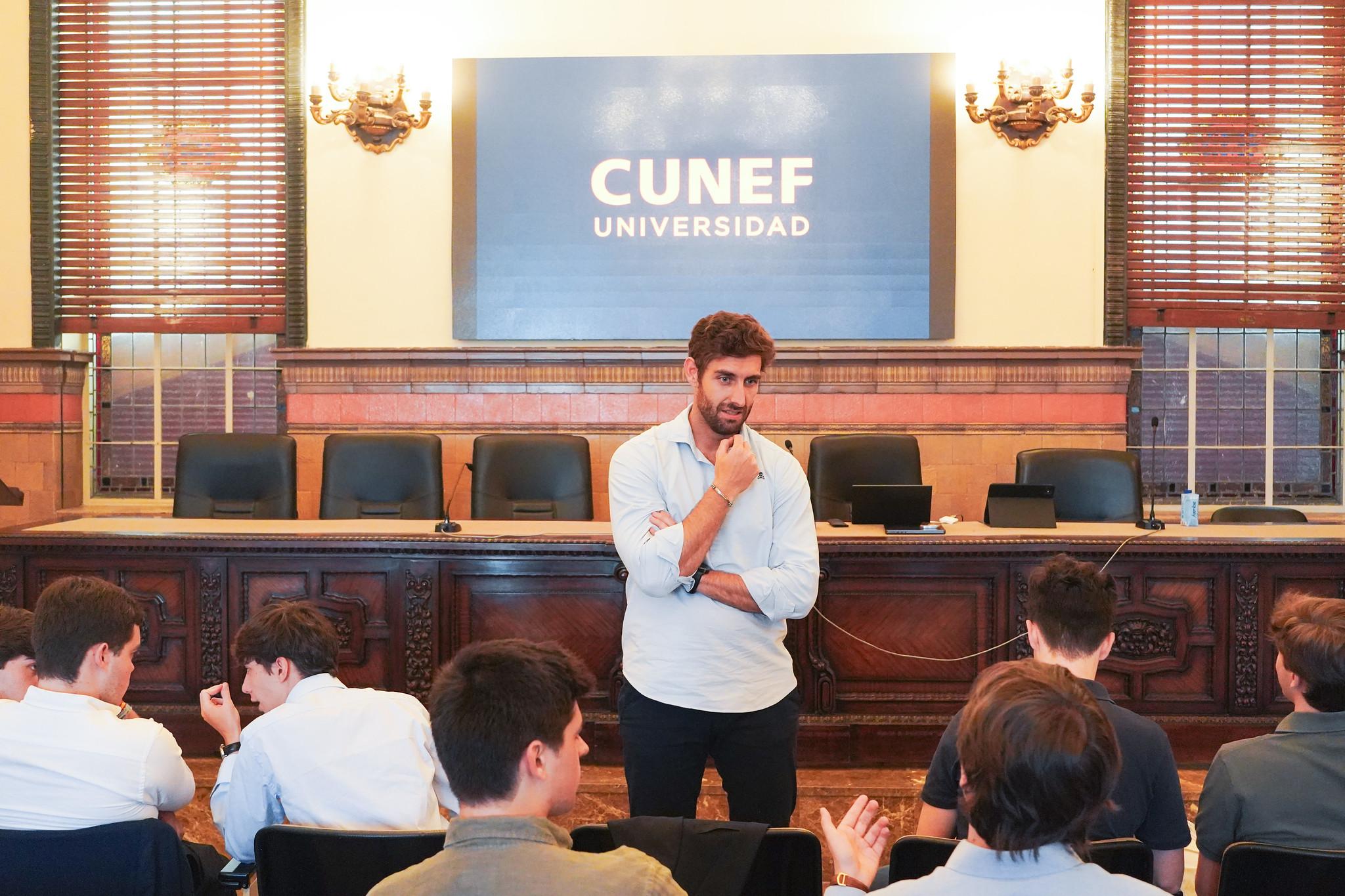 Un hombre de pie frente a un grupo de estudiantes en un aula de la universidad CUNEF.
