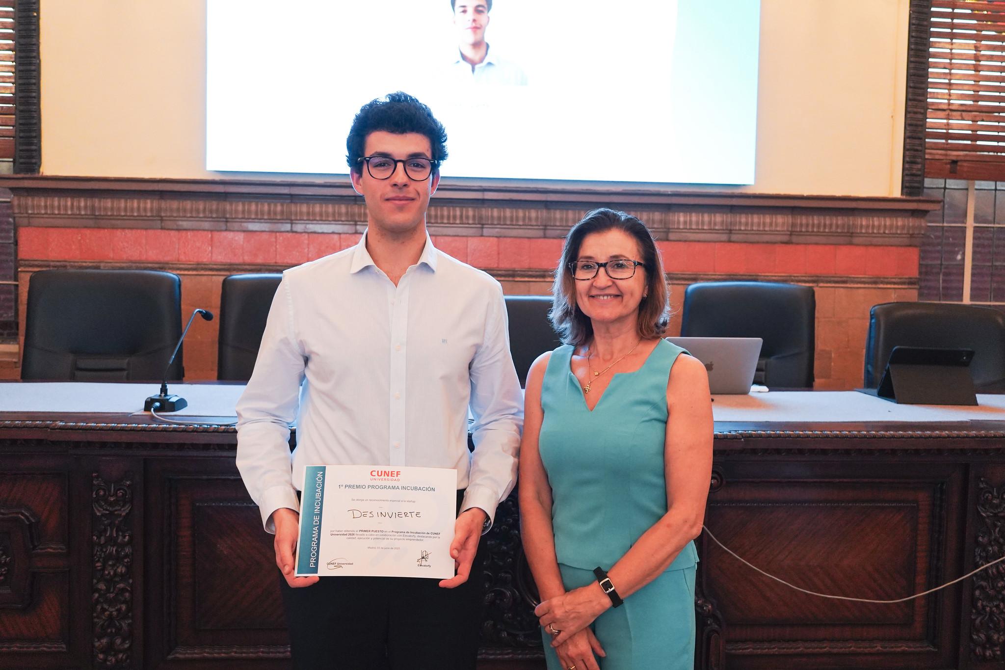 Un joven con un certificado posando junto a una mujer en un acto formal.
