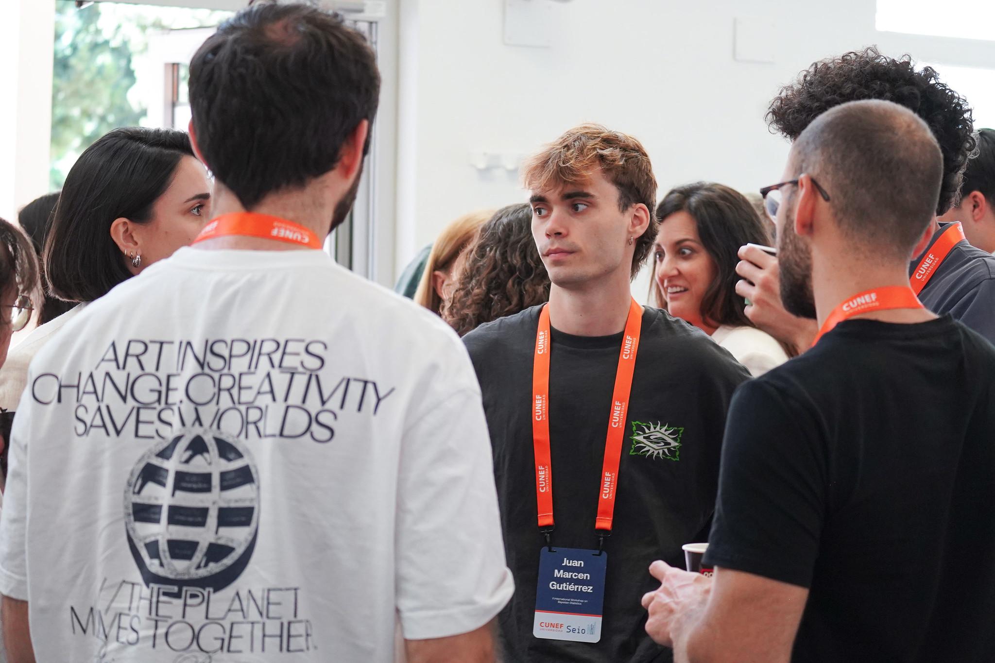 Un grupo de personas conversando en un evento con pulseras identificativas.