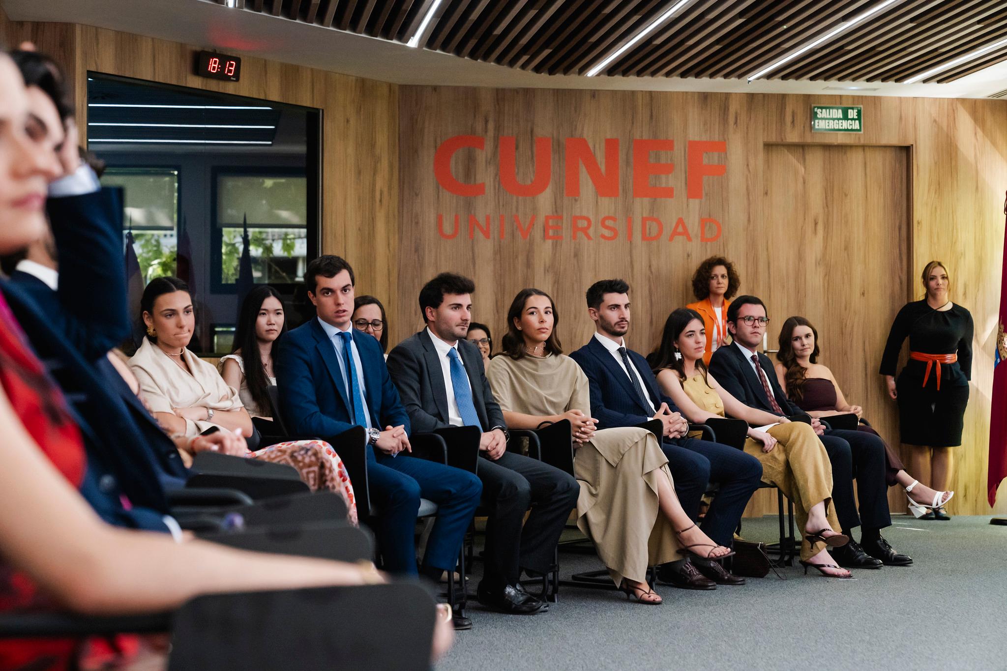 Un grupo de jóvenes vestidos formalmente se sienta en un evento en la universidad CUNEF.