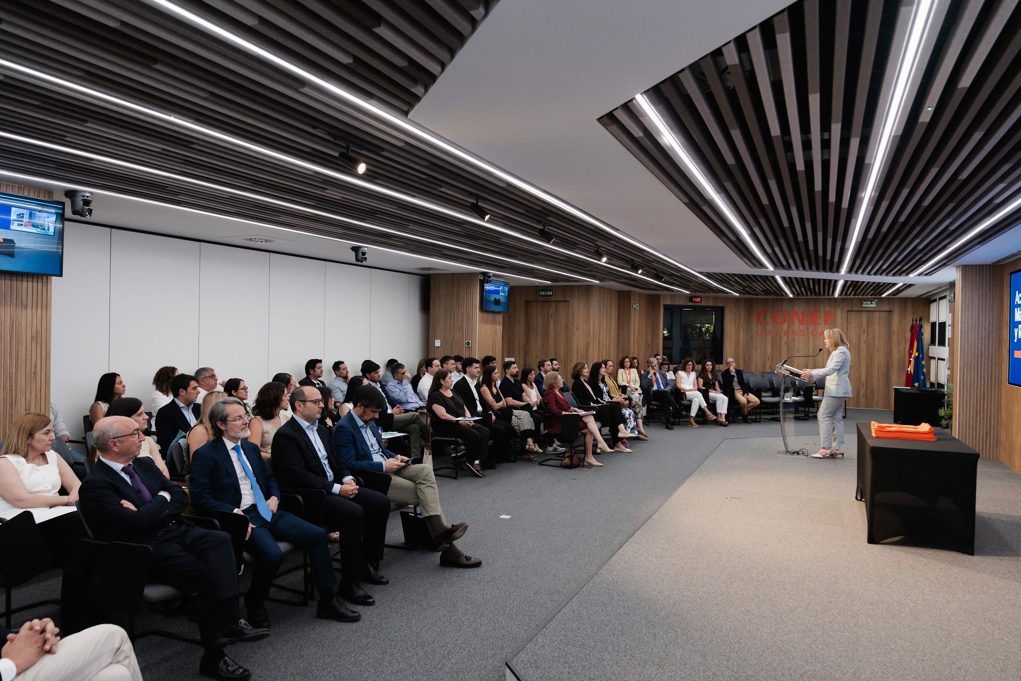 Un grupo de personas asiste a una presentación en un moderno salón de conferencias.