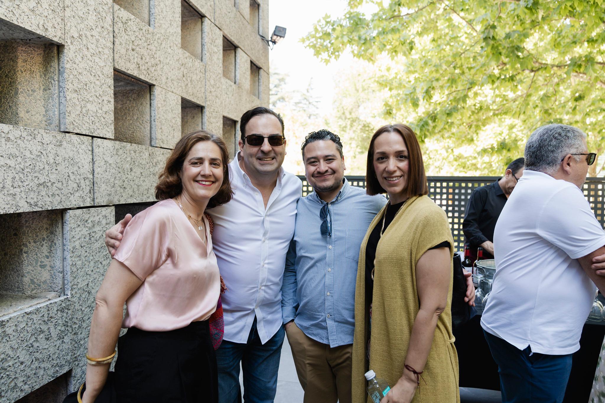 Un grupo de cuatro personas sonrientes se posa para una foto en un ambiente al aire libre.