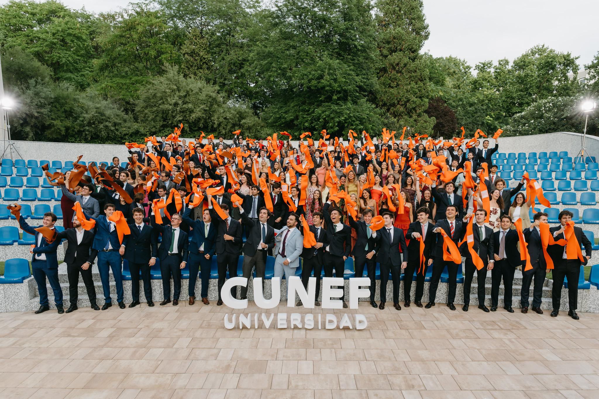 Un grupo numeroso de personas celebra su graduación en un ambiente festivo al aire libre.