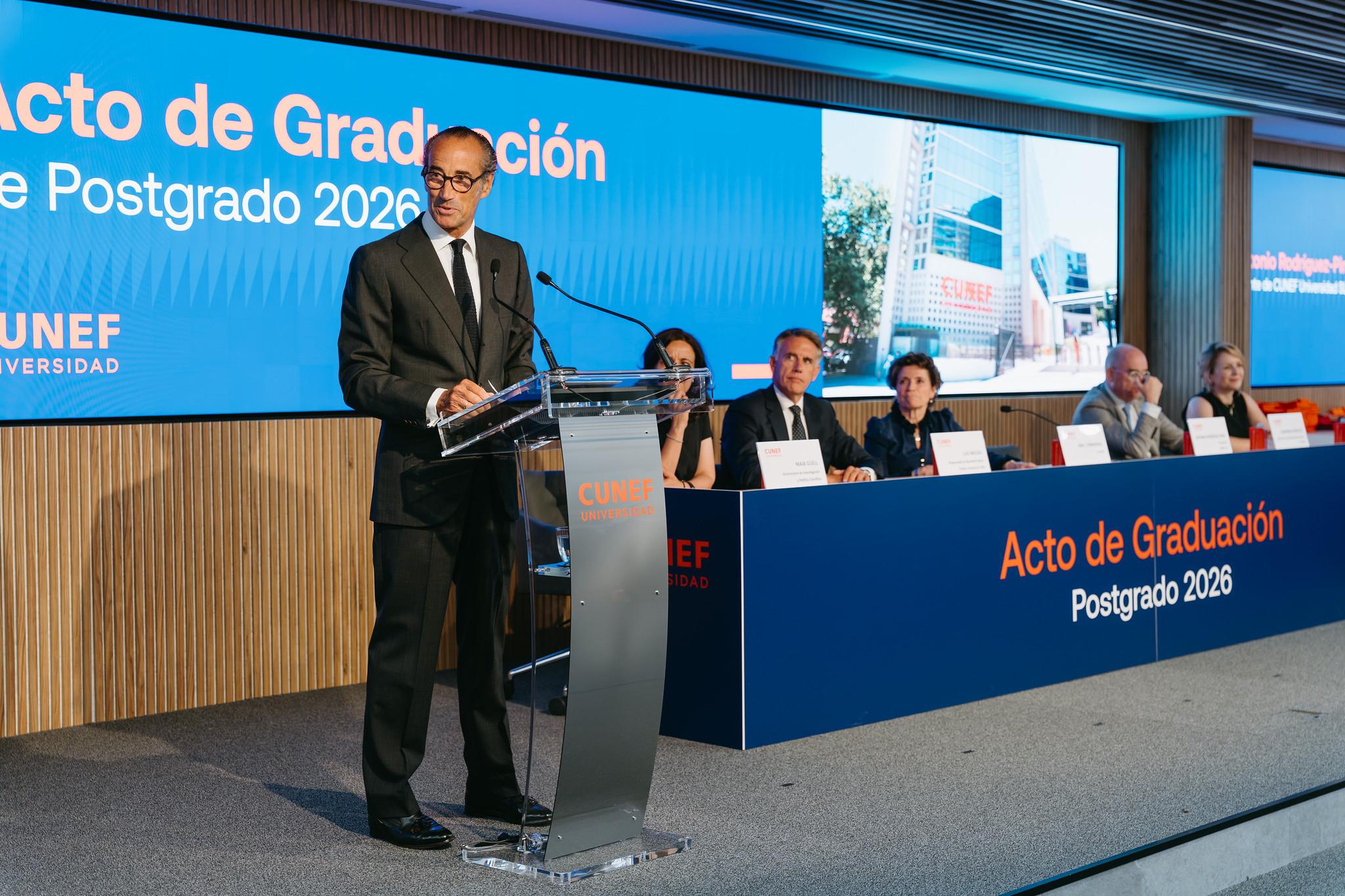 Ceremonia de graduación de un programa de posgrado con un orador principal en el podio.