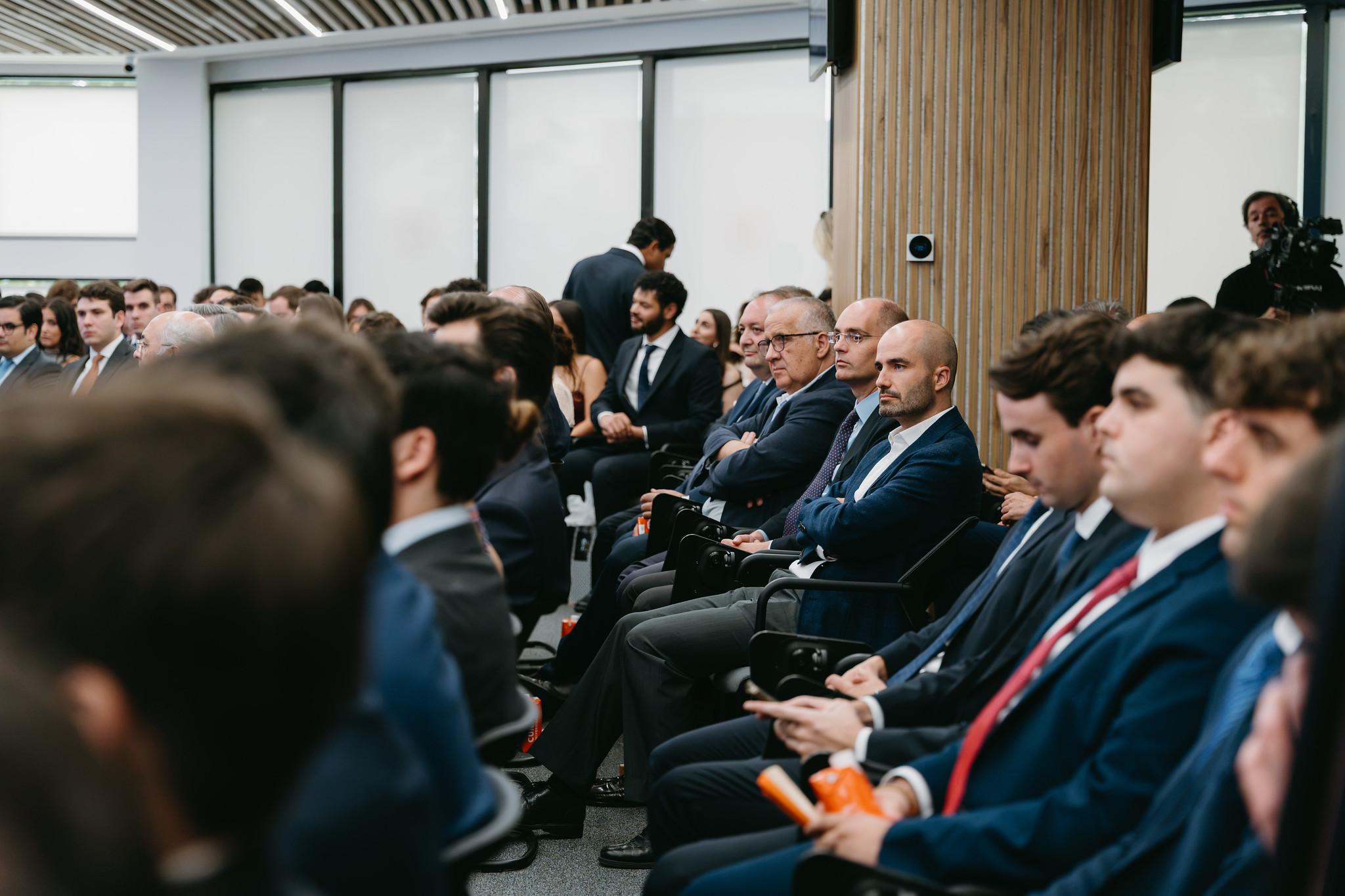 Un grupo de personas vestidas de traje sentado en un auditorio que asiste a un evento.