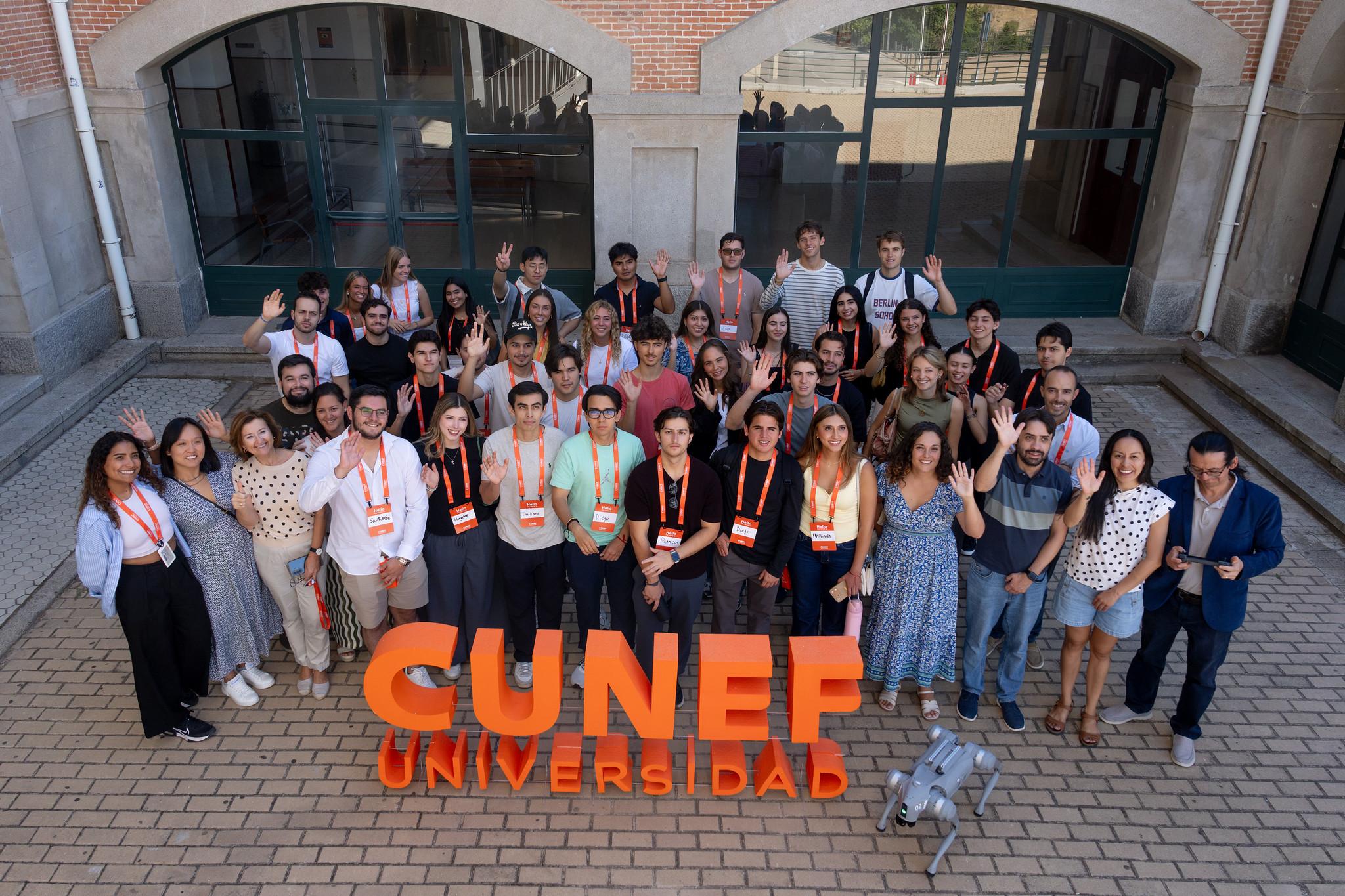 Grupo de estudiantes y educadores posando juntos frente a un letrero de la Universidad CUNEF.