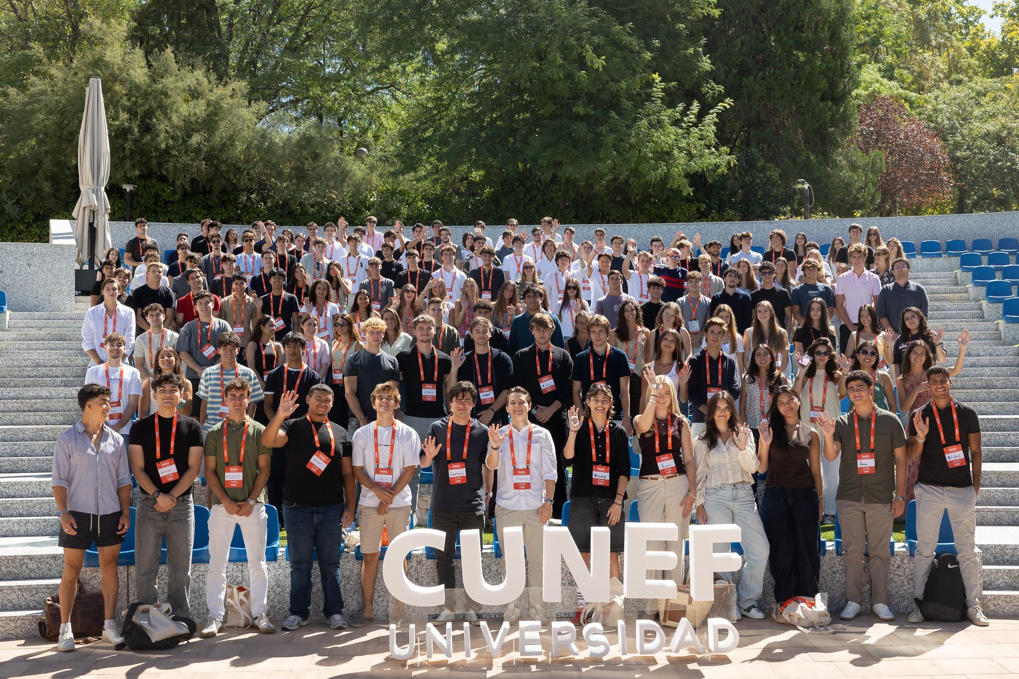 La imagen muestra a un gran grupo de estudiantes posando juntos en un ambiente exterior universitario.