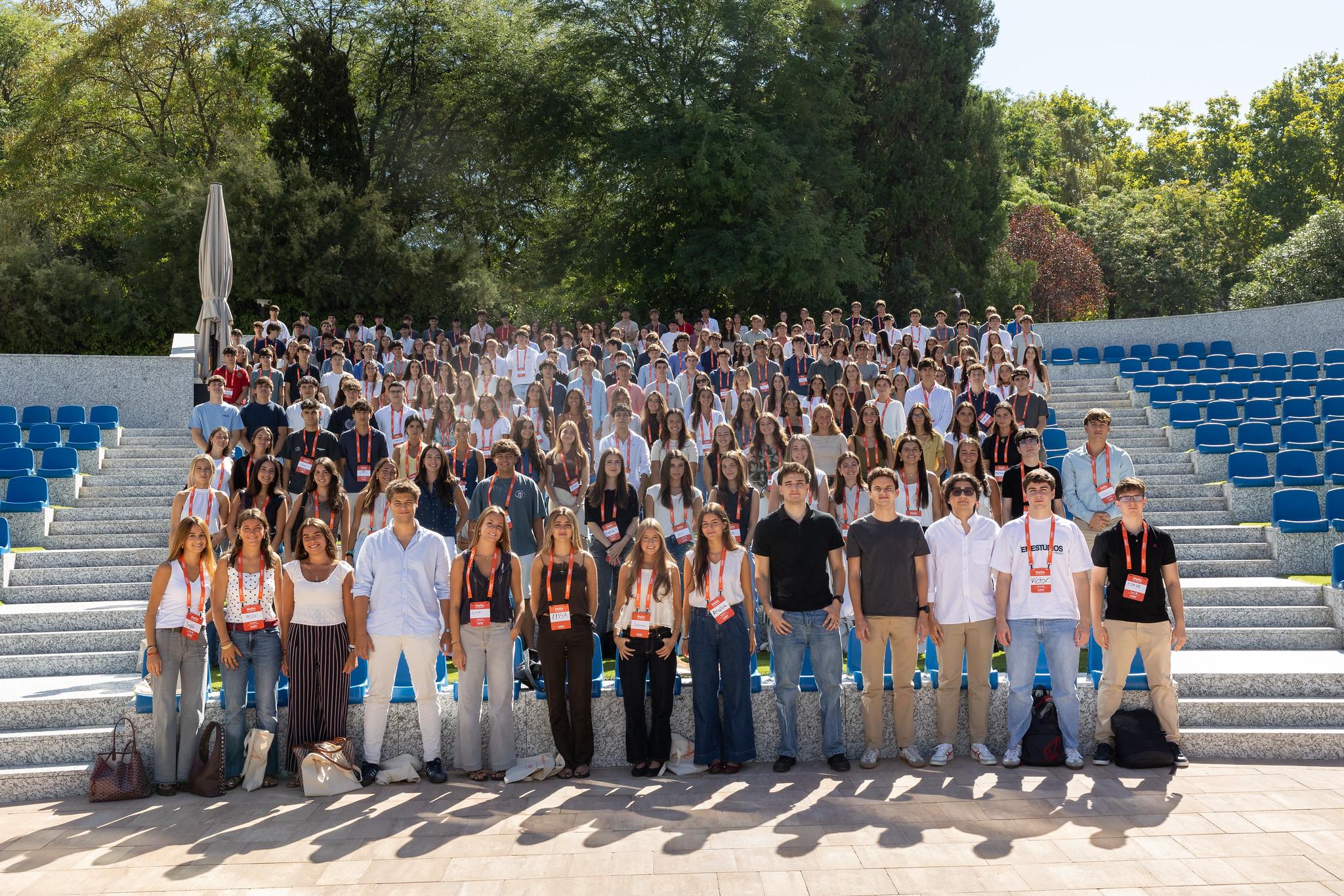 Un grupo numeroso de personas posando en un anfiteatro al aire libre en un día soleado.