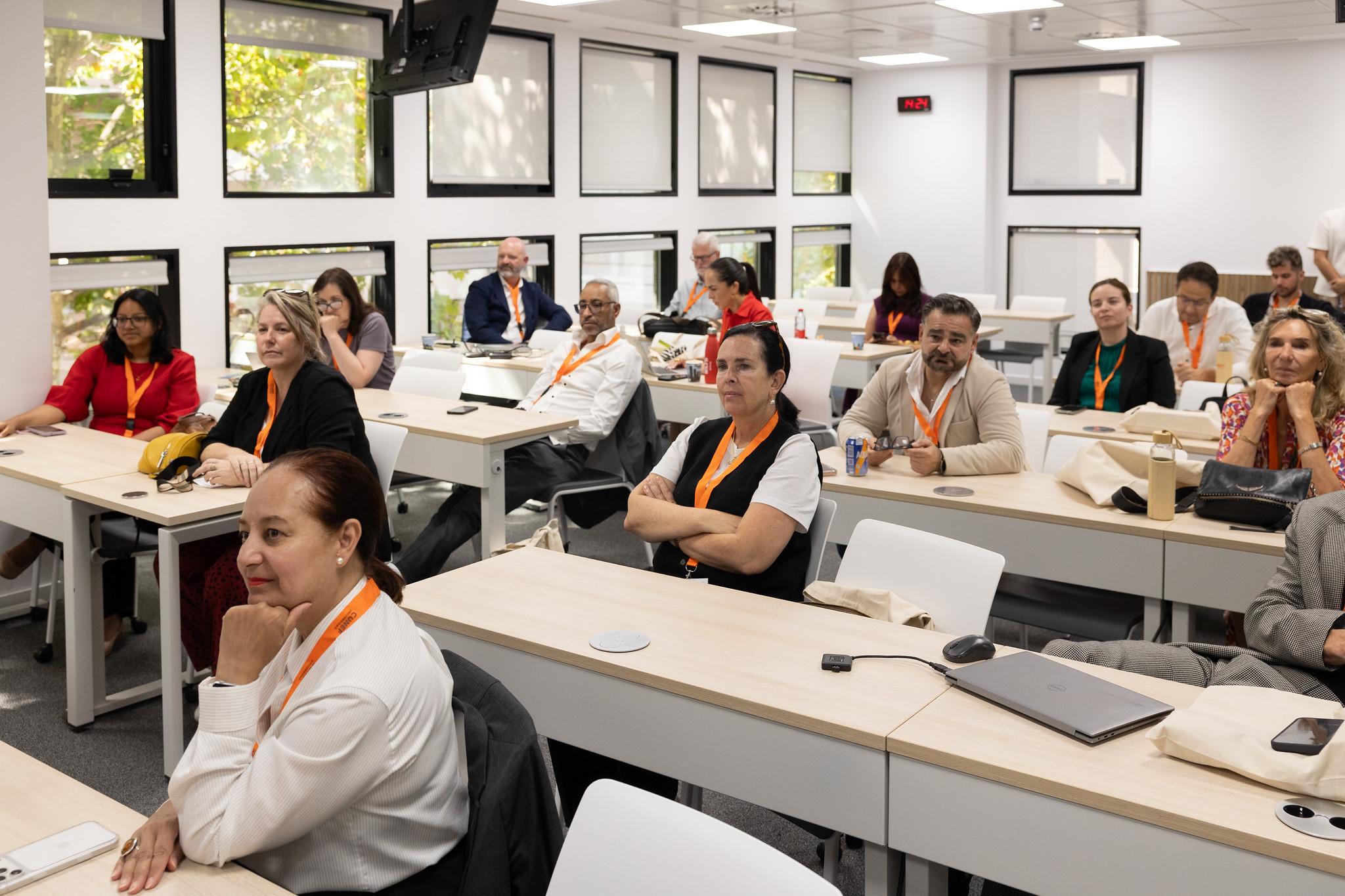 Un grupo de personas observando atentamente durante una presentación en un aula moderna.